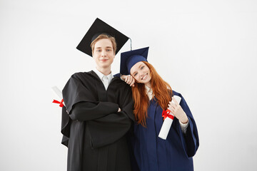 Happy graduates of university smiling posing holsing diplomas over white background.