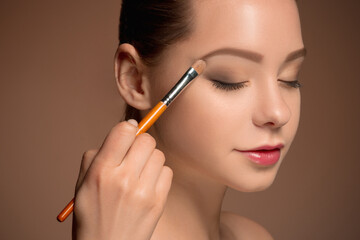 Obraz premium Beauty Girl with Makeup Brush. Perfect Skin. Applying Makeup