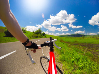 Fototapeta na wymiar Road cycling with red bicycle in great weather with blue sky and white clouds