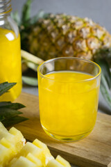 Glass of Pineapple juice with jar on a stone table.