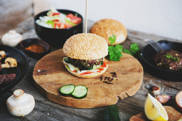 Homemade hamburger with chop and vegetables on a wooden board, country style