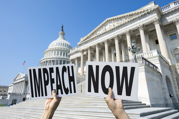 Hands of protesters holding signs on Capitol Hill demanding IMPEACH NOW referring to the president...