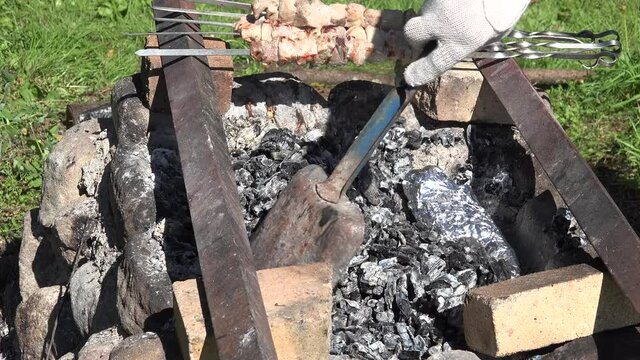 male hand put  food wrapped in foil in hot embers fireplace. 4K