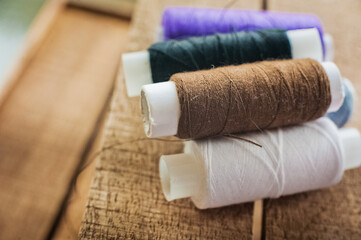 Multi-colored thread coils. Blue, purple, brown, white thread for sewing on a wooden background