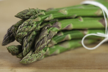Bunch of asparagus tied with white lace on a wooden background.