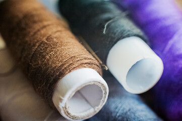 Multi-colored thread coils. Blue, purple, brown, white thread for sewing on a wooden background