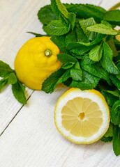Fresh juicy mint leaves and lemon on a white wooden background