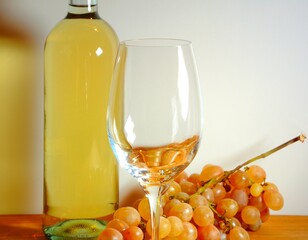 White wine bottle with glass and bunch of grapes on the wooden table