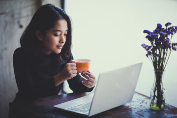 Asian  woman working with her laptop and coffee on desk, Vintage color