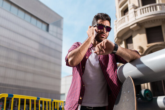 Handsome man with phone and longboard