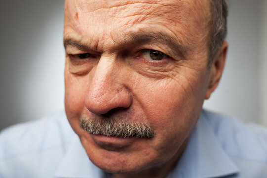 Aged man dissatisfied frowns and looks sullenly. Wrinkles on the forehead of negative events