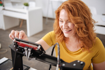 Cheerful positive woman looking at the 3d printer monitor