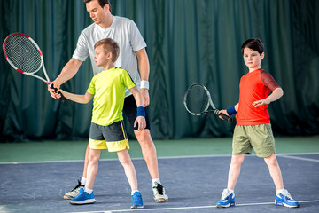Concentrated tennis player teaching kids on court
