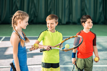 Happy children playing tennis on playground