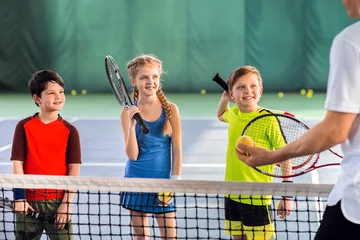 Fotobehang Joyful pupils learning to play tennis © Yakobchuk Olena