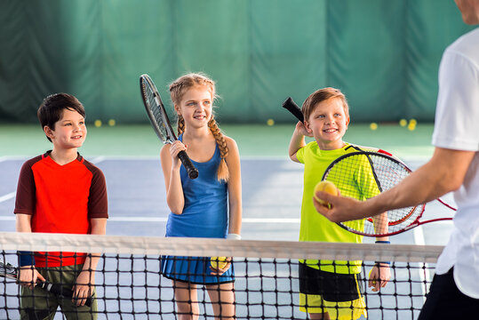 Joyful pupils learning to play tennis - Powered by Adobe
