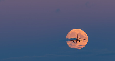 Obraz premium Silhouette of landing airplane at moon rise