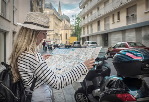 Woman tourist on the street in Paris, look on map under sunlight