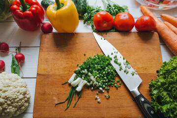 Cooking salad still. Knife and cut fresh green onion on chopping board. Vegetables border frame.