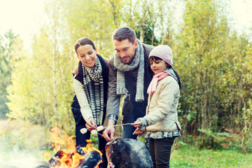 happy family roasting marshmallow over campfire