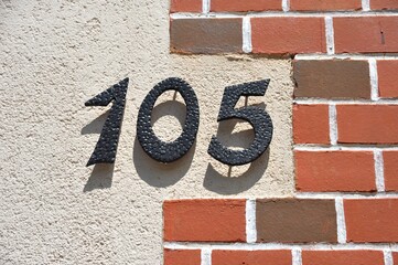 Hausnummer 105 aus gehämmertem Stahl an einer Ziegelwand