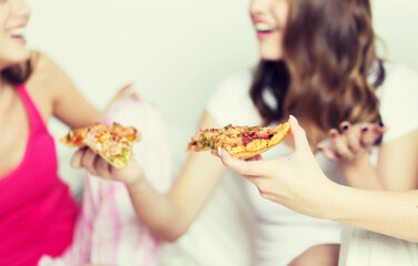 happy friends or teen girls eating pizza at home