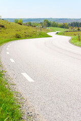Curvy road through scenic landscape. Hills and meadows along the winding road. Location Brosarp in Scania, Sweden. Copy space on road.