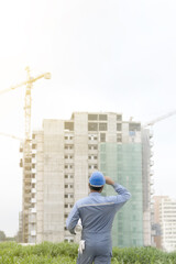 Obraz na płótnie Canvas worker or engineer holding drawing in hands on background of new apartment buildings and construction cranes on background..