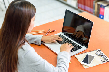 Fototapeta premium Beautiful businesswoman uses a laptop computer in the office. With the phone and notebook placed on the wood table. Business and Technology Concepts