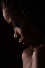 Close up portrait of dark skinned model on black backstage. Light and shadow portrait.