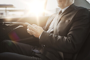 senior businessman texting on smartphone in car