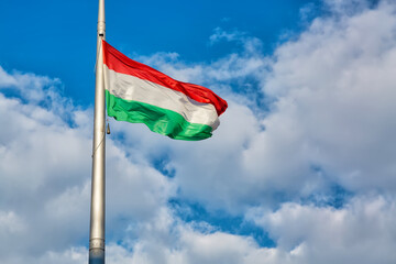 Hungary flag on sky background with clouds