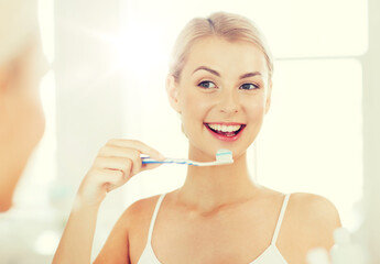 woman with toothbrush cleaning teeth at bathroom