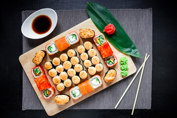 Japanese sushi rolls, soy sauce, ginger and chopsticks on a dark table. Top view. Flat lay. Japanese traditional food
