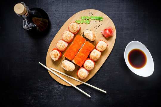 Sushi rolls, soy sauce and chopsticks on a black background. Japanese natural food.  Top view. Flat lay.