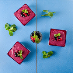 Top view Multiple berry smoothie on blue ceramic background. Well being, Healthy eating, Detox or Diet concept. Selective focus Flat lay