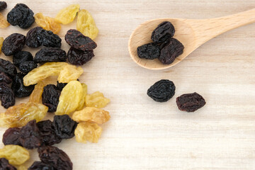 Dried raisins in wooden spoon on wood table.