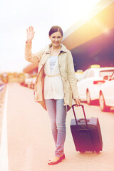 smiling young woman with travel bag over taxi