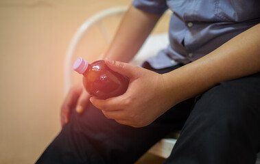Naklejka premium A Fat man sits and holding a bottle of medicine for himself on the bed. He has heart disease. Health care concept. Close-up