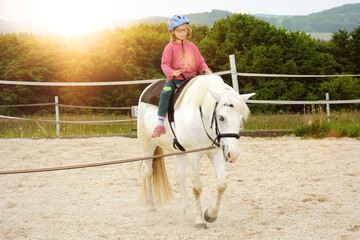 Kind bei Reitunterricht in Reitschule reitet auf Pferd