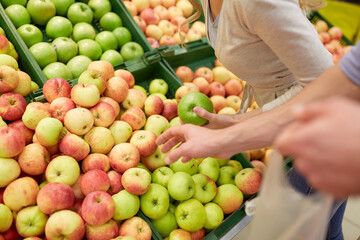 happy couple buying apples at grocery store