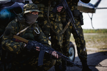 Photos of a group of military men with a gun in front of a helicopter