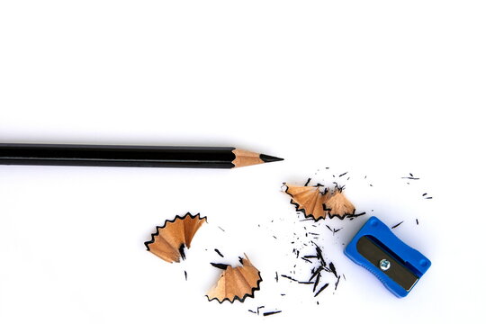 A black pencil , pencil sharpener and pencil scraps on the white background.