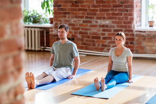 man and woman doing yoga staff pose at studio