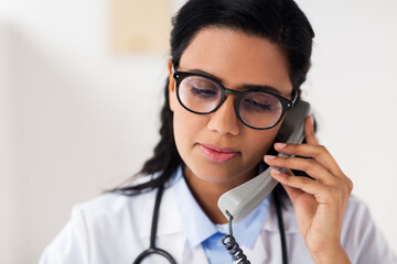 doctor in glasses calling on phone at hospital