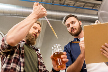 men with pipette testing craft beer at brewery