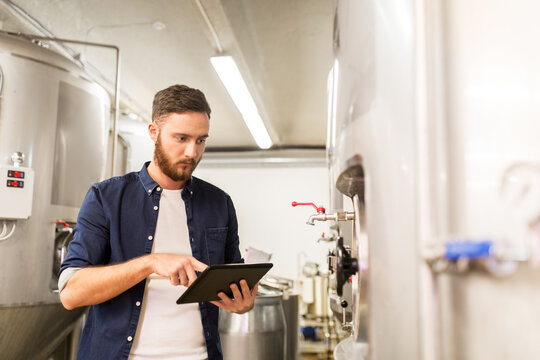 man with tablet pc at craft brewery or beer plant