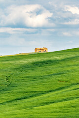 Fototapeta na wymiar Grass field with a house on the hill