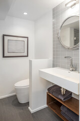 Naklejka na ściany i meble Shot of clean modern bathroom with tiled wall and round mirror