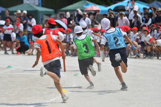 小学校の運動会のリレーで競争する子供たち